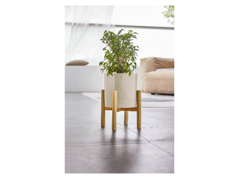 Een witte plantenpot op een houten standaard met een groene plant.