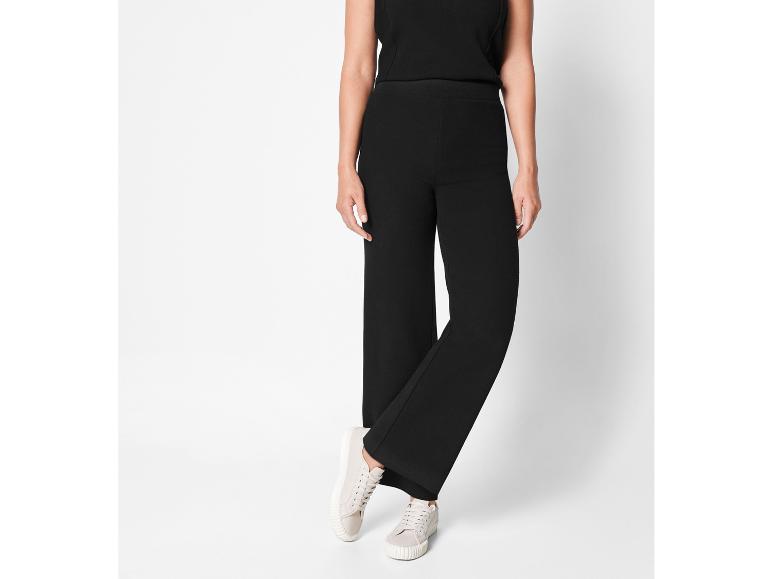 Zwarte broek met wijde pijpen en witte sneakers.