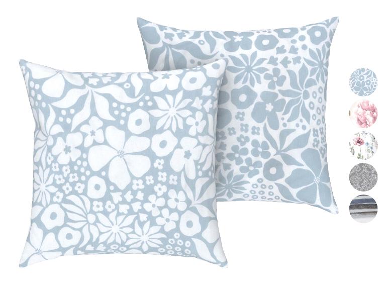 Twee blauwe kussens met witte bloemenpatronen.