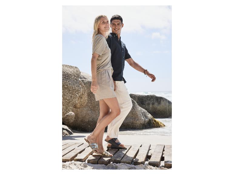 Koppel in sandalen op een rotsachtig strand.