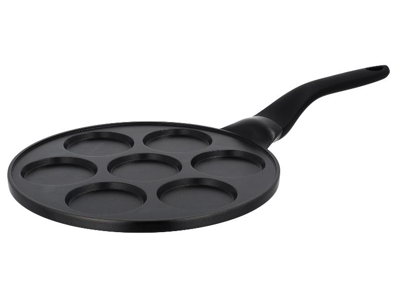 Zwarte pannenkoekenpan met zeven ronde uitsparingen en een handvat.