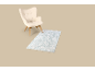 Beige fauteuil met een lichtblauw vloerkleed op een beige achtergrond.