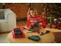 Vrouw in kersttrui gebruikt lijmpistool om cadeaus in te pakken, met mutsen op tafel.