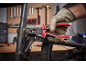 Een hand met werkhandschoen gebruikt een combinatietang om een bout op een fietsframe vast te draaien.