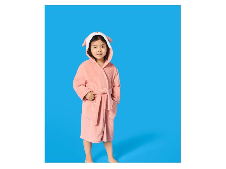 Meisje in roze badjas met dierenorenkap, glimlachend.