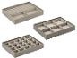 Set van drie grijze sieradenorganizers met diverse vakken voor ringen en accessoires.