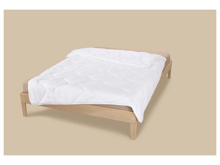 Bed met licht houten frame, bruin hoeslaken en wit, doorgestikt dekbed.
