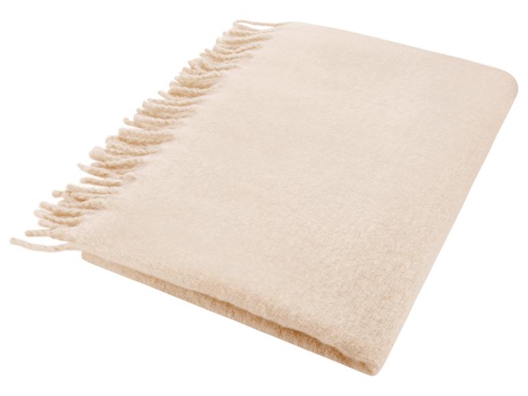 Beige deken met franjes, opgevouwen op een witte achtergrond