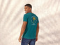 Een man draagt een turquoise t-shirt met een print van een palmboom.