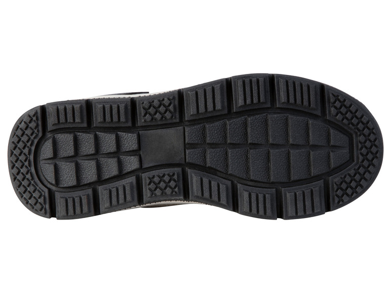 De onderkant van een zwarte sneaker met een grof profiel.