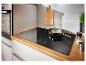 Moderne keuken met inductiekookplaat, oven en groenten die in een pan koken.