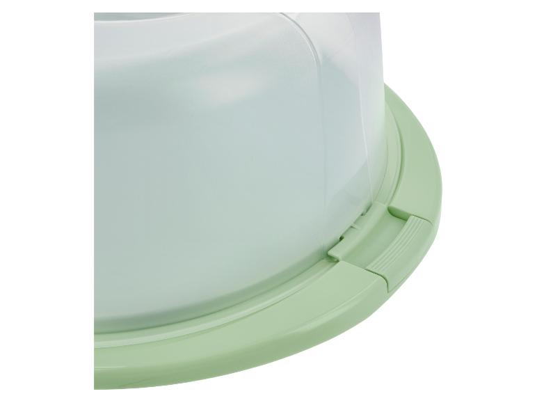 Close-up van een lichtgroene taartdoos met een transparante koepeldeksel.