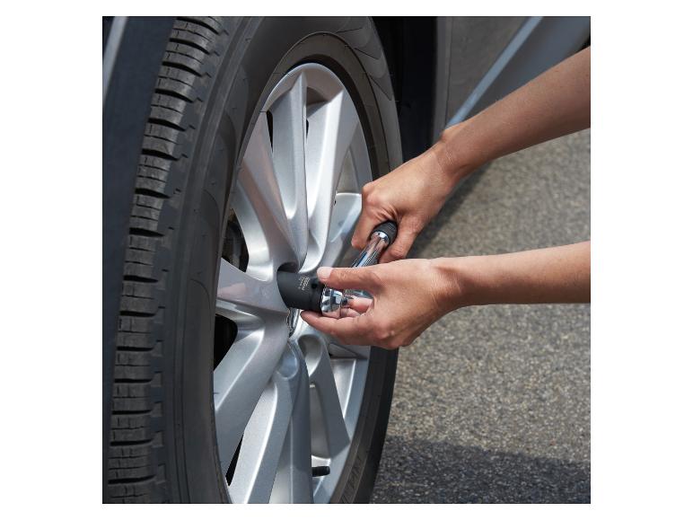 Een persoon gebruikt een dopsleutel om een wielmoer aan een auto vast te draaien