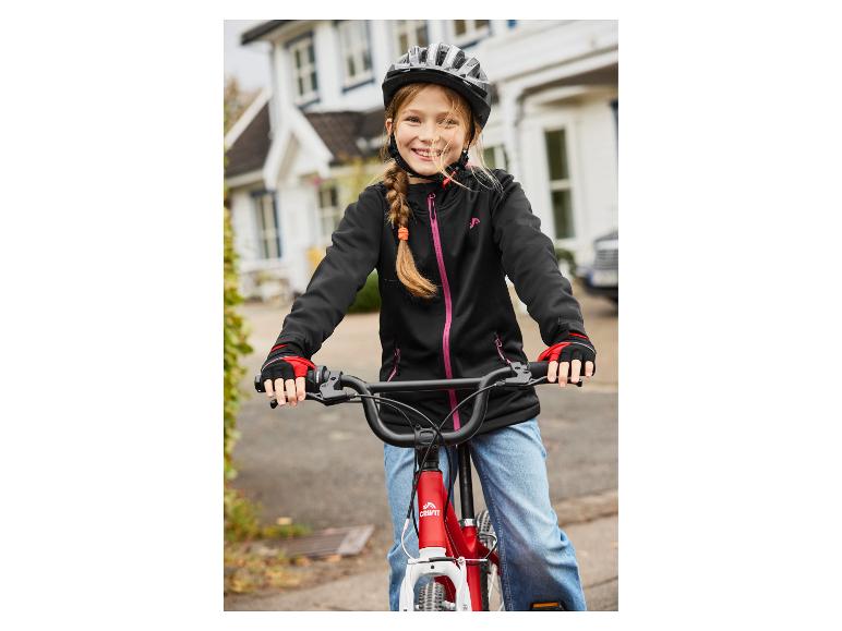 Lachend meisje met fietshelm en jas op een rode fiets.