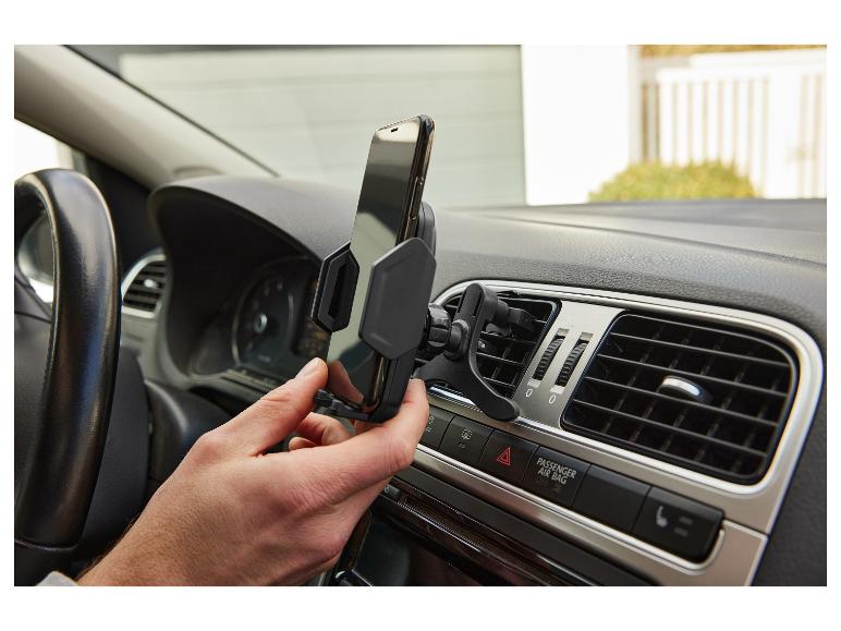 Handen plaatsen een automobiel telefoonhouder in een ventilatierooster.