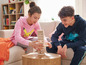 Twee kinderen spelen een spelletje blokken op een salontafel.