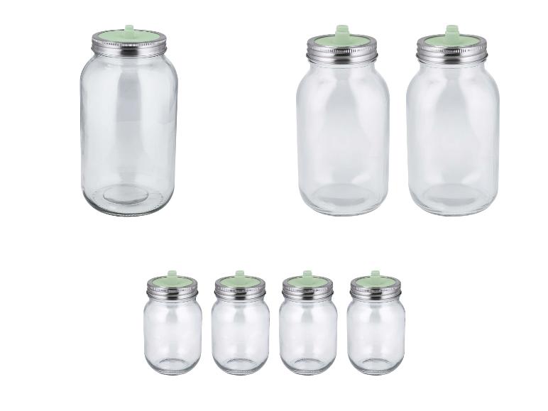 Sets van heldere glazen potten met metalen deksels en groene fermentatieventielen.