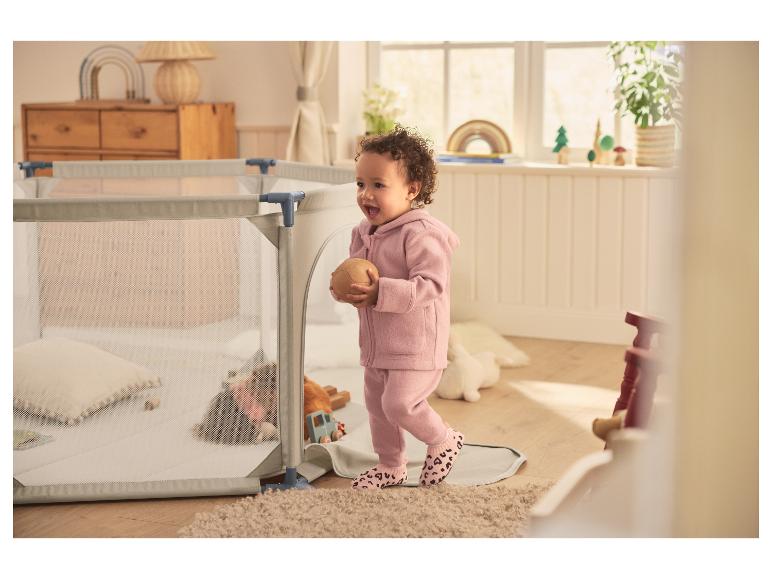 Peuter in roze LUPILU® wollen broek met een bal naast een box