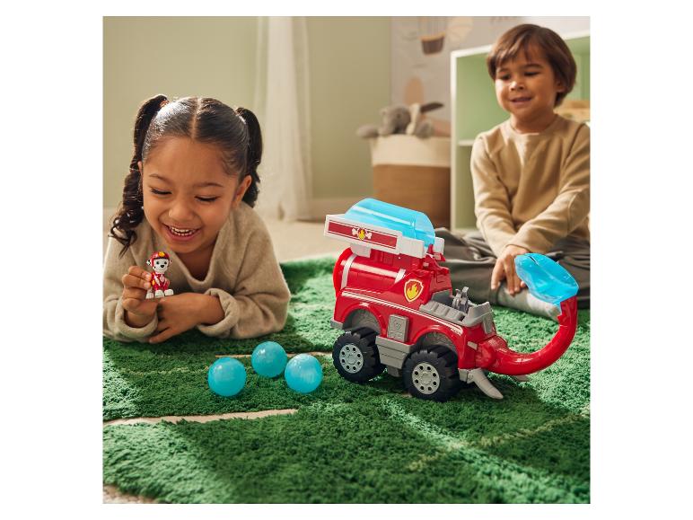 Twee kinderen spelen met een Paw Patrol voertuig en figuur op een groen tapijt.