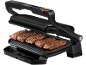 Open elektrische grill met vier gekookte biefstukken en een lekbak.