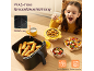 Meisje aan tafel, naast een airfryer met eten en kommen met fruit en groenten.