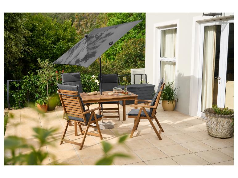 Buiten eethoek met houten tafel, stoelen met grijze kussens en grote parasol op een terras.