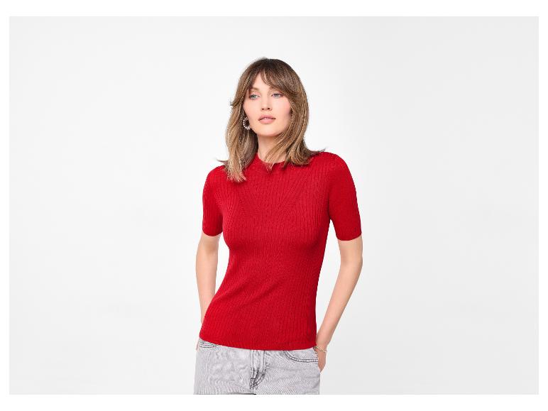 Vrouw in een rood geribbeld T-shirt met korte mouwen en lichte jeans