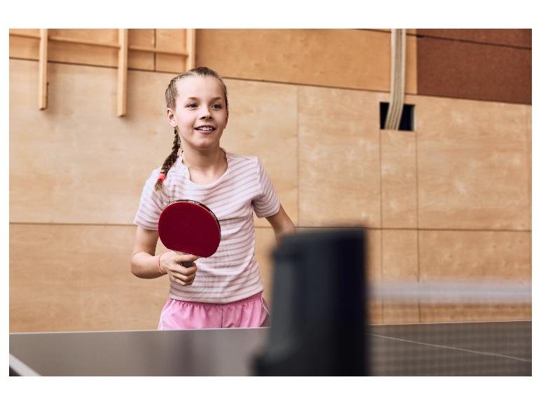 Meisje speelt tafeltennis, met een rood batje in haar hand.