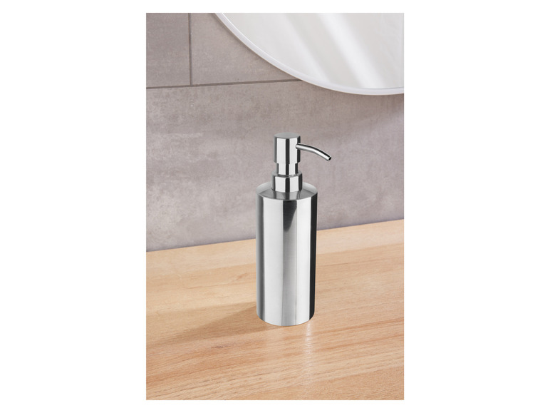 Een zilveren zeepdispenser op een houten aanrecht.