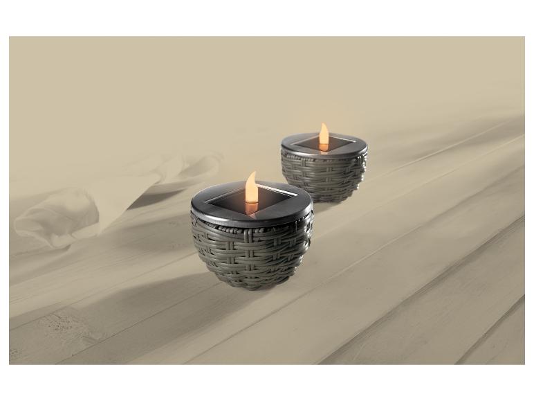 Twee solarlampen met vlameffect op een houten tafel met wit tafelkleed.