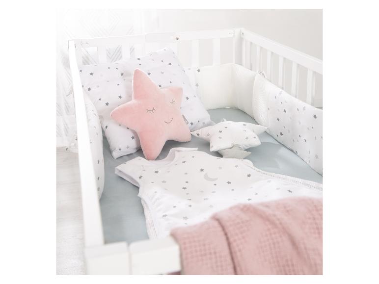 Babybedje met sterrenbeddengoed en een roze stervormig kussen.