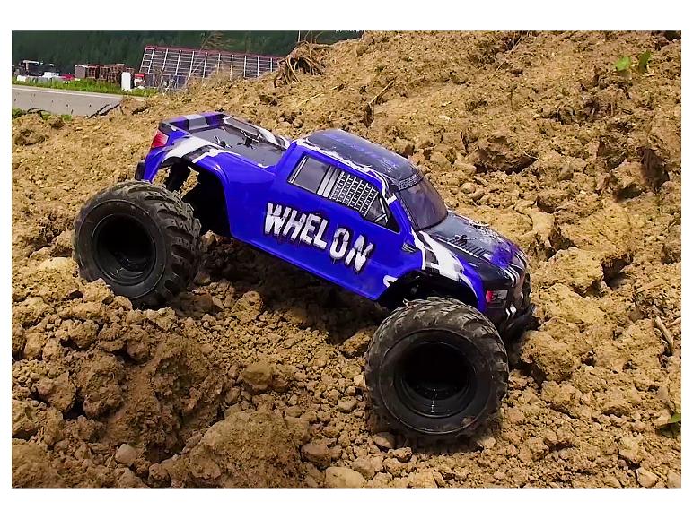 Een blauwe Whelon monstertruck rijdt een heuvel op.