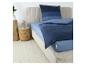 Bed met blauw gestreept beddengoed en licht hoofdeinde, met houten nachtkastjes ernaast.