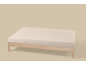 Licht matras op een houten bedframe met een lichtbeige achtergrond.