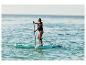 Vrouw peddelt op een paddleboard in zee, met reddingsvest.