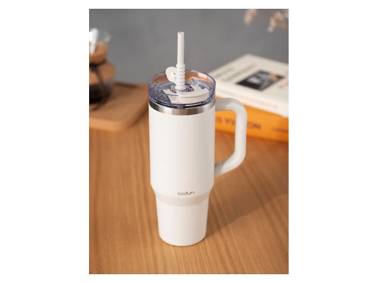 Witte Bodum thermosbeker met handvat en rietje op een houten tafel.