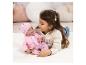 Meisje speelt met een babypop in het roze, liggend op een wit vloerkleed.