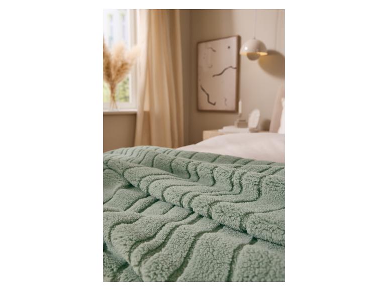 Zachte groene LIVARNO home deken op een bed.