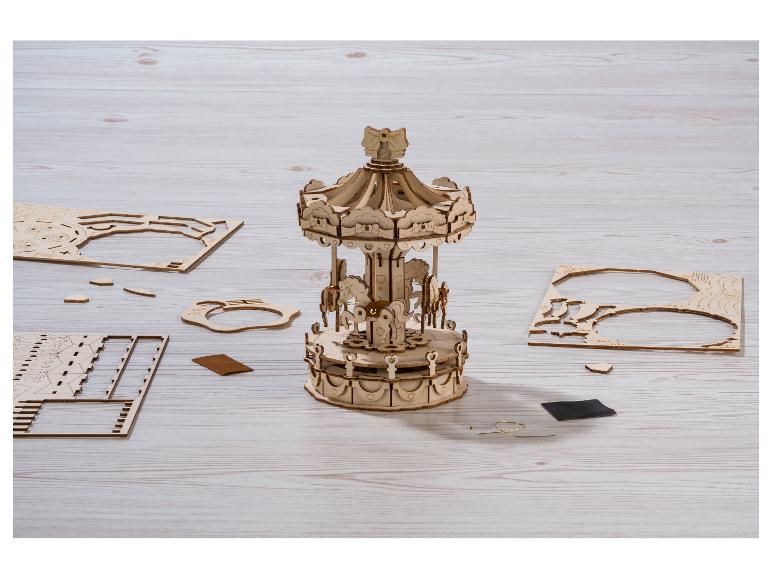 Gemonteerde houten carrousel en puzzelstukjes op een houten tafel.