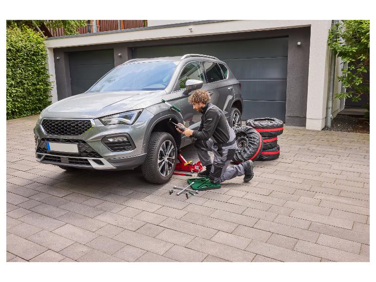 Man verwisselt autobanden, met autokrik en moersleutels.