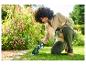 Vrouw gebruikt een Parkside grastrimmer in een bloementuin.