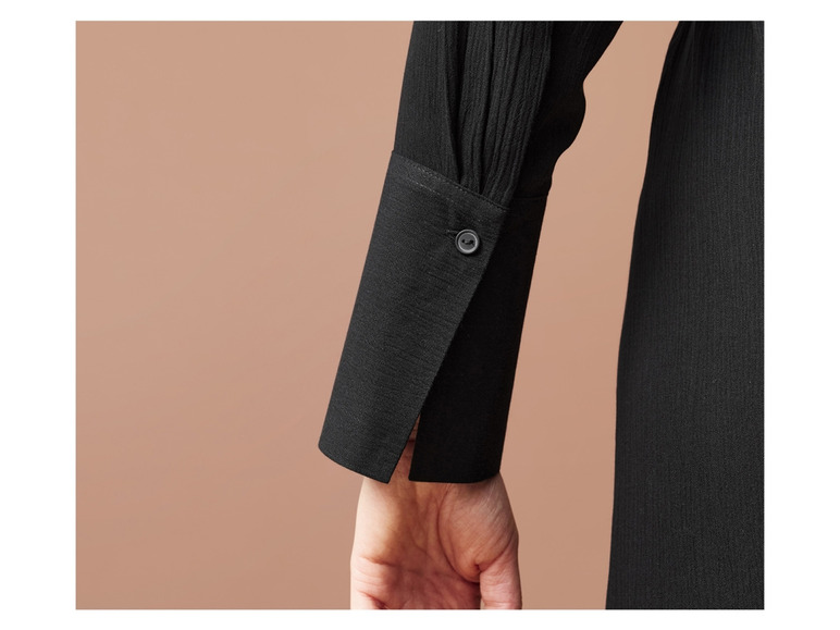 Close-up van een zwarte blouse met lange mouwen.