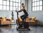 Een vrouw fietst op een zwarte hometrainer in een moderne woonkamer.