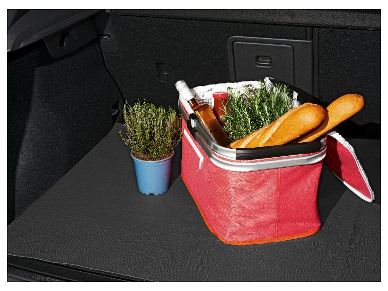 Picknickmand met baguettes, kruiden en een fles in een kofferbak.