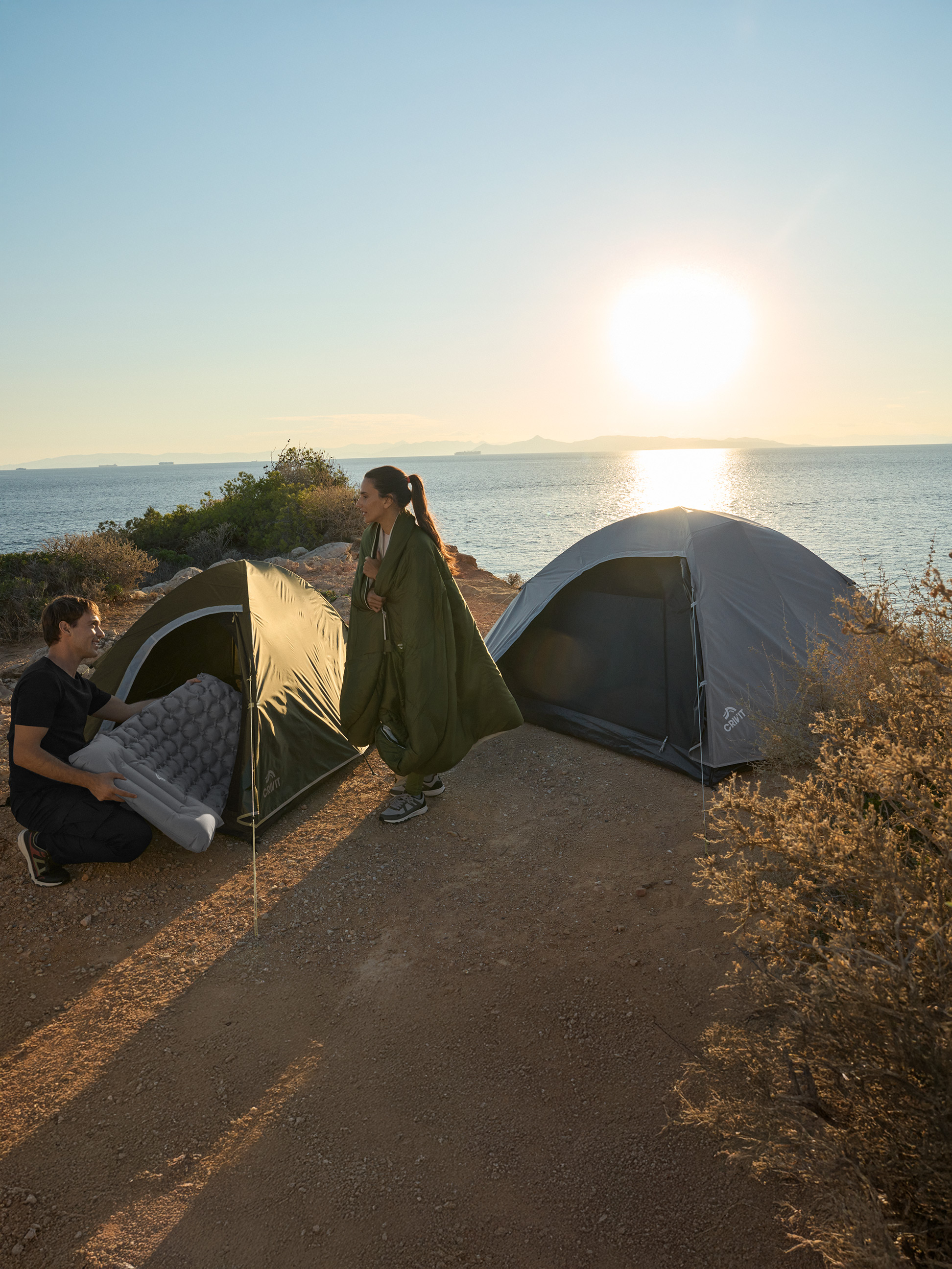 Twee mensen kamperen aan zee met twee Crivit tenten en een luchtbed.