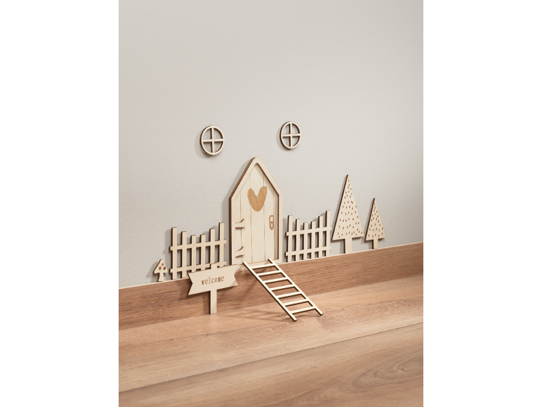 Houten wanddecoraties, inclusief een sprookjeshuis, hekken en bomen.