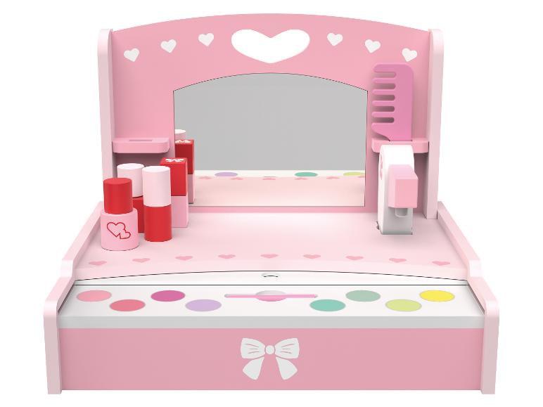 Roze kinderkaptafel met spiegel, cosmetica en accessoires.