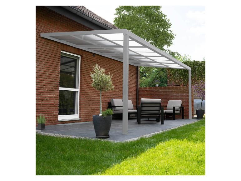 Grijze terrasoverkapping met transparant dak boven een buitenlounge met meubels en planten.