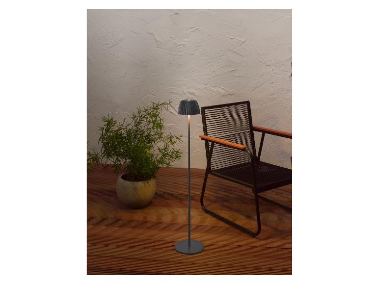 Moderne vloerlamp en potplant op een houten terras met een stoel.