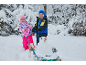 Twee kinderen in winterkleding met een slee en een kleine sneeuwpop in een besneeuwd landschap.